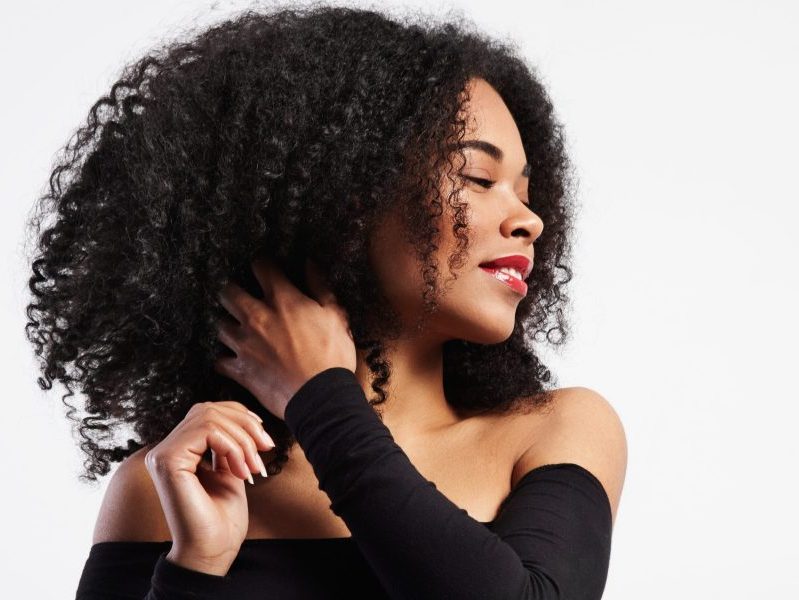 black woman touches her curly hair